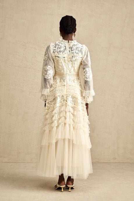 A long white maxi dress with sheer tulle layers and colorful floral embroidery details throughout featuring a flowing silhouette and delicate Capucine design