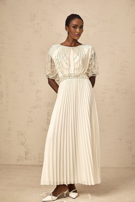 A long white pleated maxi dress adorned with crystal embellishments featuring a flowy silhouette and elegant design