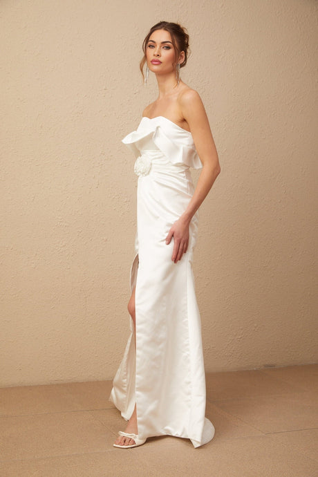 A long white satin dress with floral appliques adorning the bodice and skirt flowing to full length