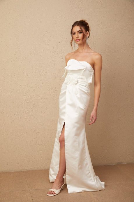 A long white satin dress with floral appliques adorning the fabric featuring a maxi length design