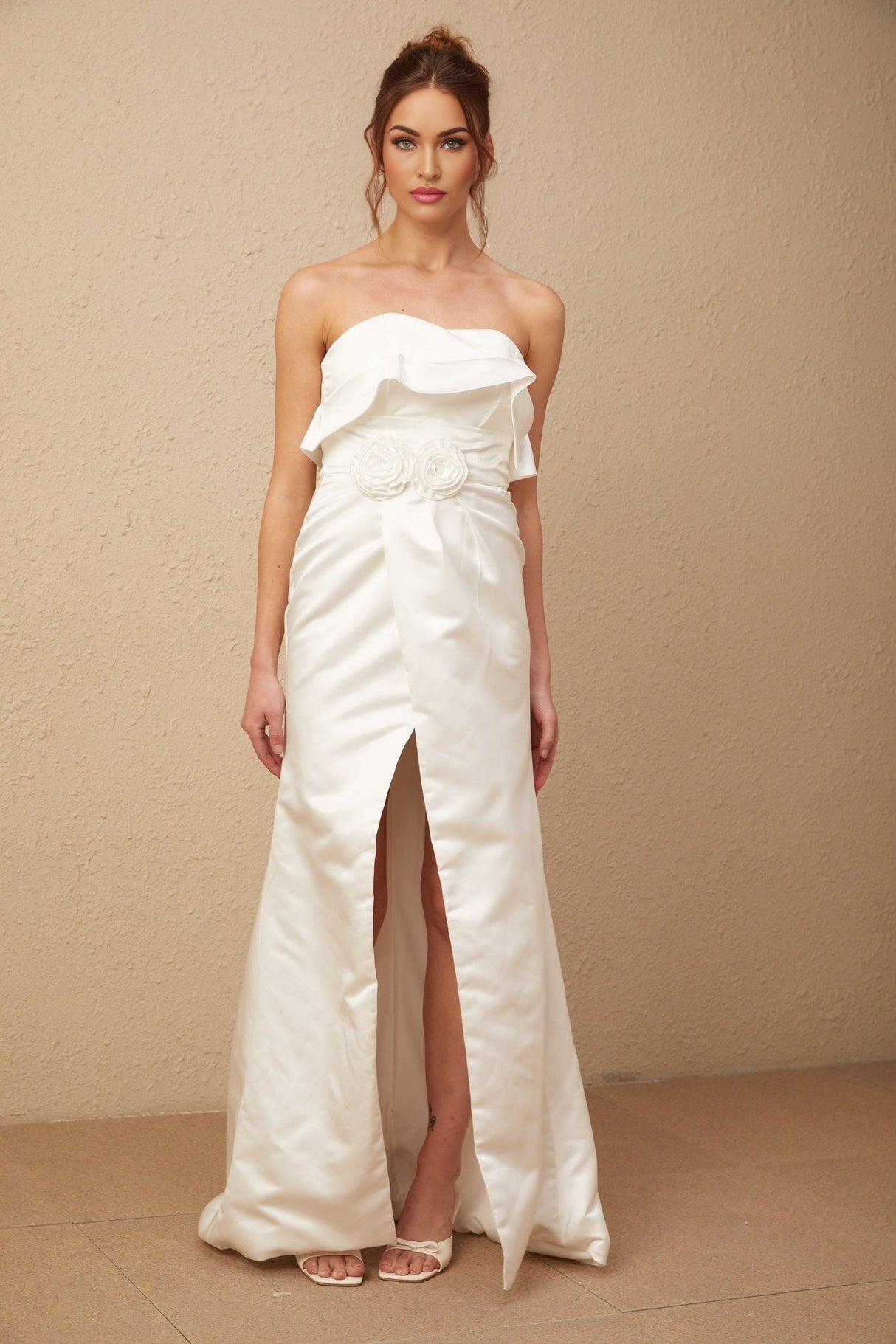 A long white satin maxi dress with floral applique details featuring a fitted bodice and flowing skirt