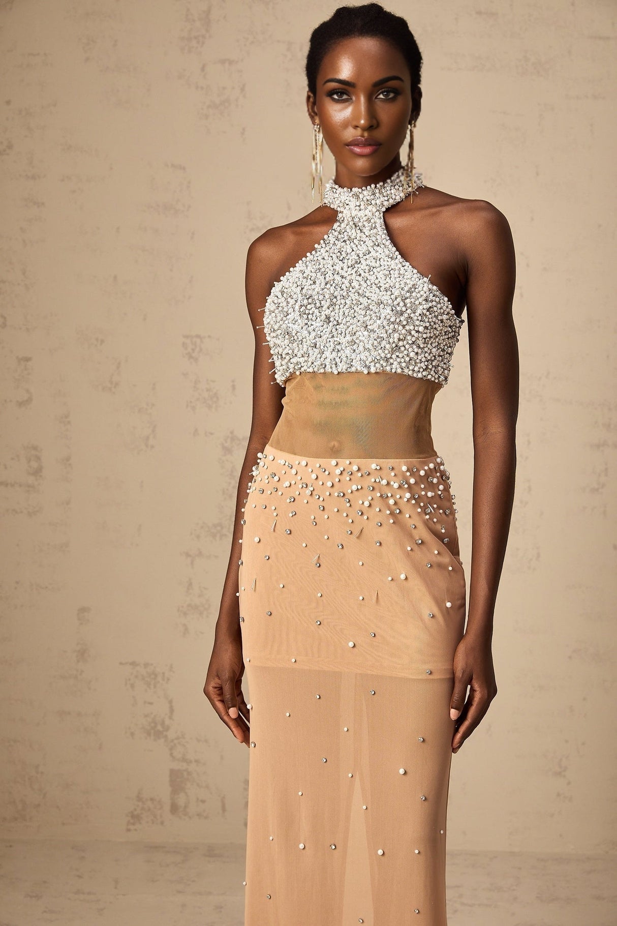 A long white semisheer maxi dress adorned with small faux pearls and featuring a flowy silhouette