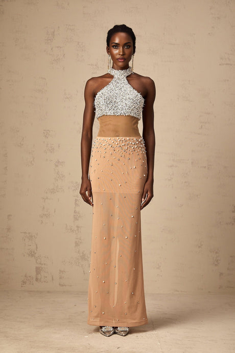 A long white semisheer maxi dress with faux pearl embellishments adorning the fabric named Rosa