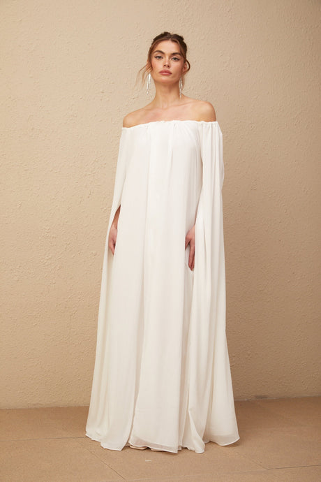 A long white tulle maxi dress with a capelike design and draped detailing named Patrizia