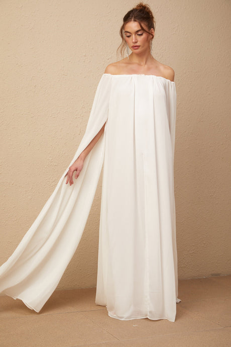 A long white tulle maxi dress with a flowing cape design and elegant draping