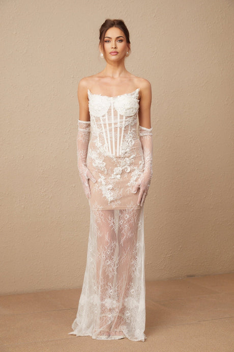 A long white tulle maxi dress with floral embroidery and a corset style bodice featuring delicate straps and a flowing skirt
