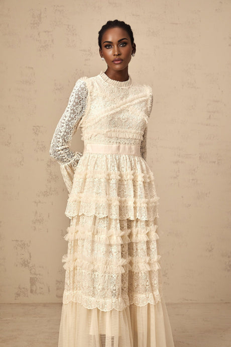 A long white tulle maxi dress with lace panels and ruffled details featuring a romantic and ethereal design in neutral tones
