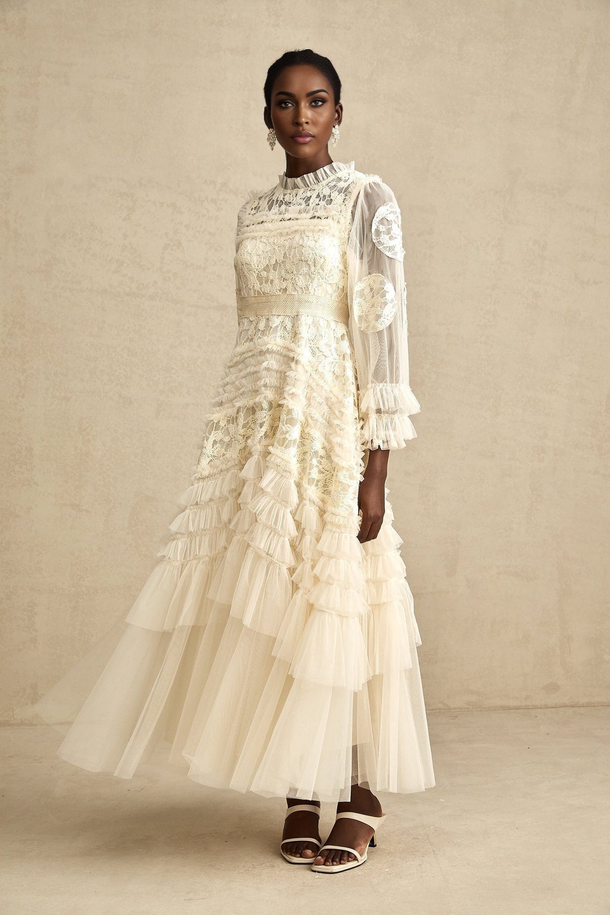 A long white tulle maxi dress with layers of sheer fabric featuring delicate floral embroidery in pastel colors