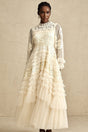 A long white tulle maxi dress with multiple layers featuring delicate floral embroidery in vibrant colors covering the bodice and scattered throughout the skirt