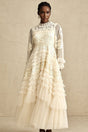A long white tulle maxi dress with multiple layers featuring delicate floral embroidery in vibrant colors covering the bodice and scattered throughout the skirt