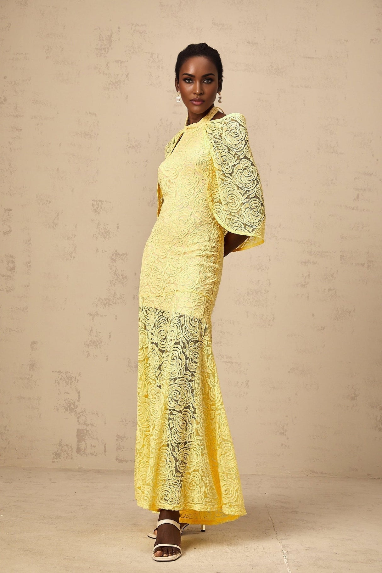A long yellow maxi dress with a cape design made from delicate chantilly lace featuring a flowing silhouette and feminine details