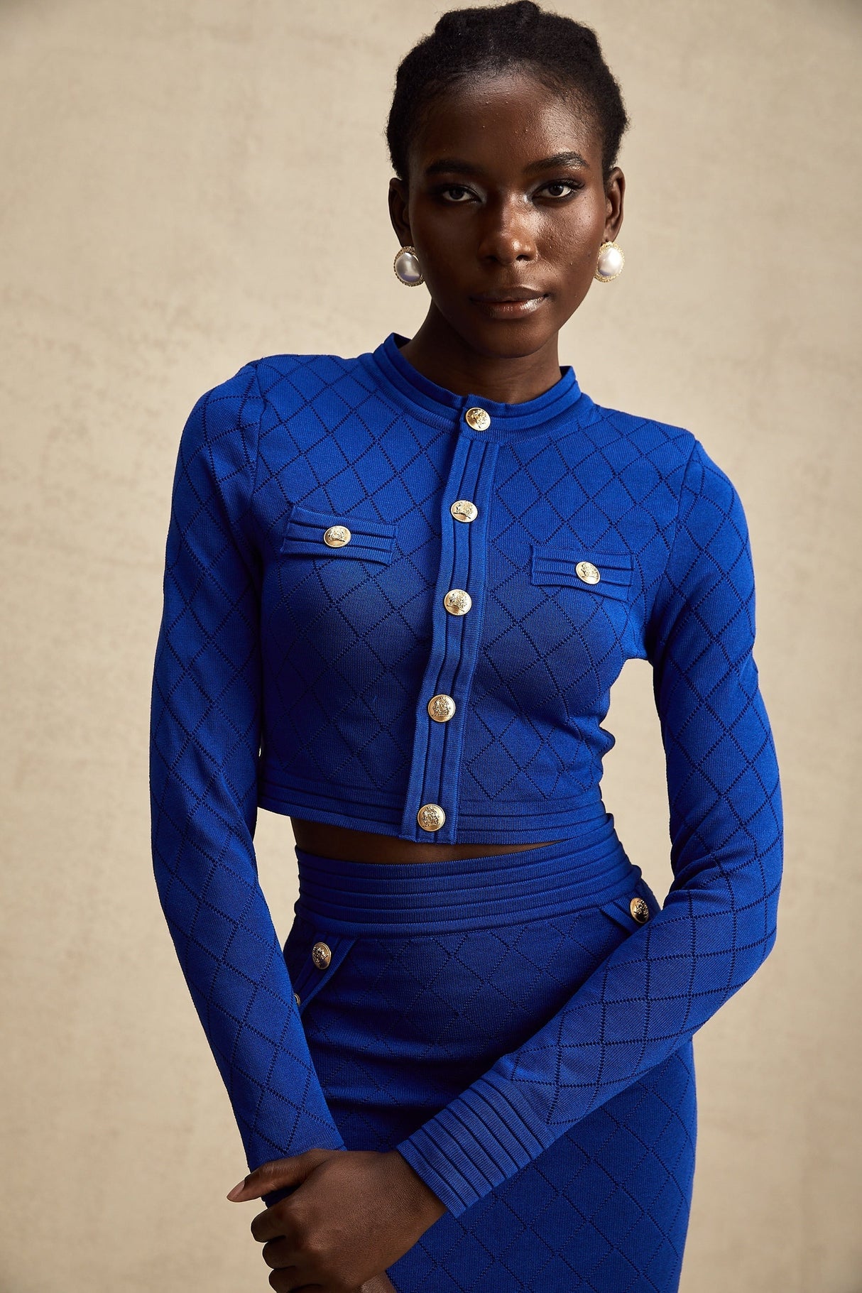 A matching set consisting of a blue knitted top and skirt The top features button details Both pieces are made by Maelys