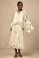A matching set featuring a floral print blouse with ruffles and a coordinating dress in the same pattern and colors