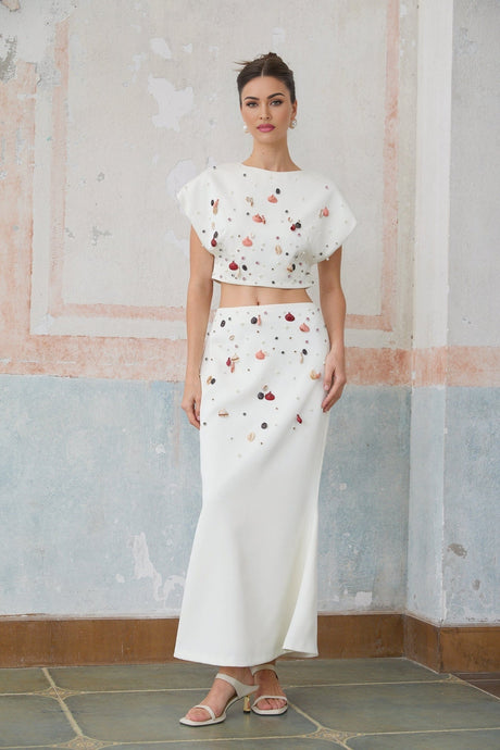 A matching set featuring a white top and skirt adorned with shell embellishments named Delphine