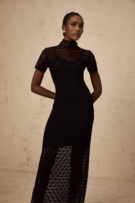 A model wearing a black semisheer knit midi dress with a fitted silhouette and long sleeves