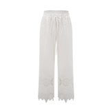 A model wearing a matching set consisting of a cropped top and trousers in white The top features lace trim and cutout details The trousers are high waisted and flared The set has a romantic and feminine style