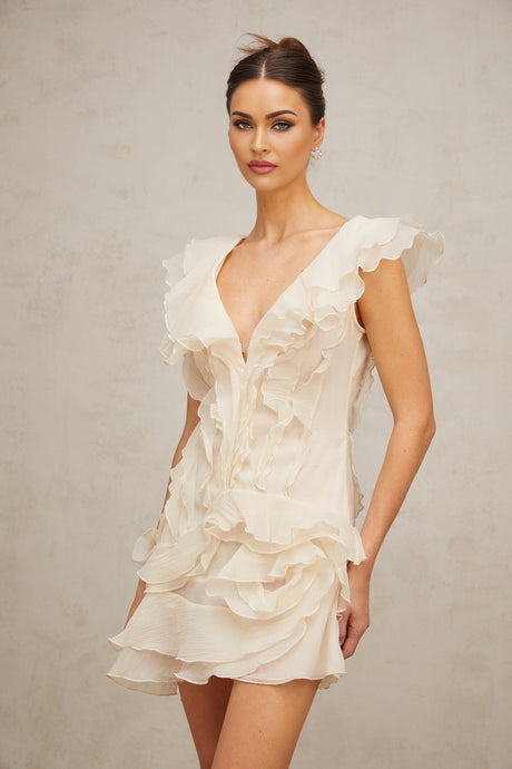 A model wearing a pink mini dress with layered ruffles and faux flower embellishments