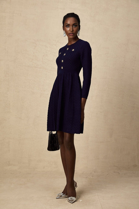 A navy blue mini dress with a basket weave texture worn by a model standing against a plain backdrop