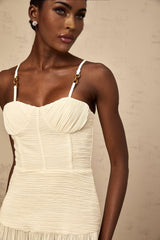 A neutral colored long pleated maxi dress with a side slit and a fitted silhouette named Felicie