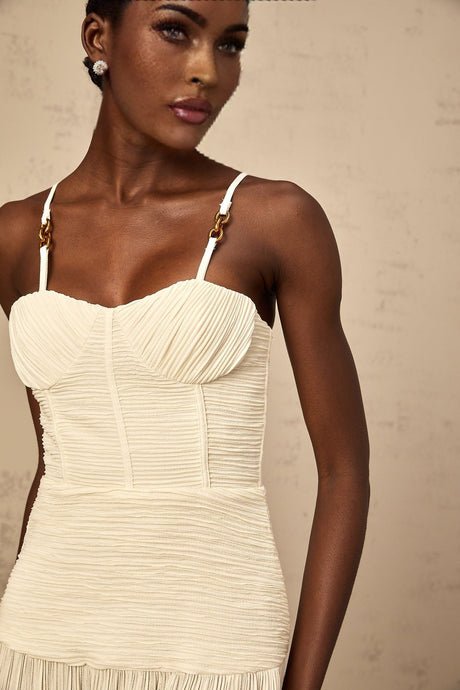 A neutral colored long pleated maxi dress with a side slit and a fitted silhouette named Felicie