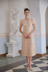 A neutral colored midi dress with crochet detailing and faux flower embellishments modeled on a female figure