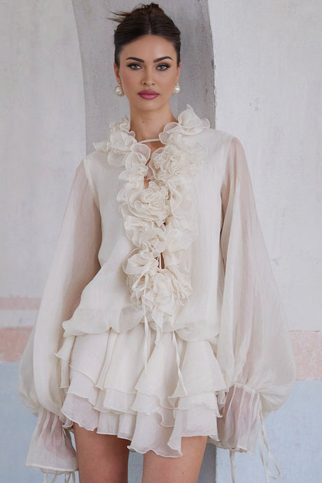 A neutral colored mini dress with a tiered skirt featuring floral appliques and a short hemline named Zephyrine