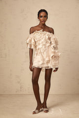 A neutral colored mini dress with an asymmetric design featuring a cerise flounce detail