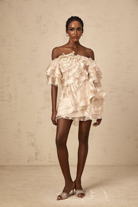 A neutral colored mini dress with an asymmetric design featuring a cerise flounce detail