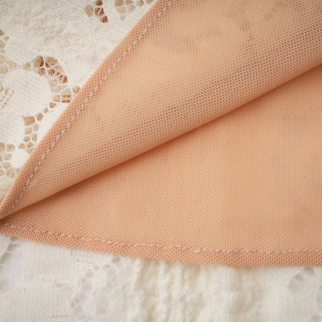 A neutral colored mini dress with floral lace pattern and flared cuffs called Emeline