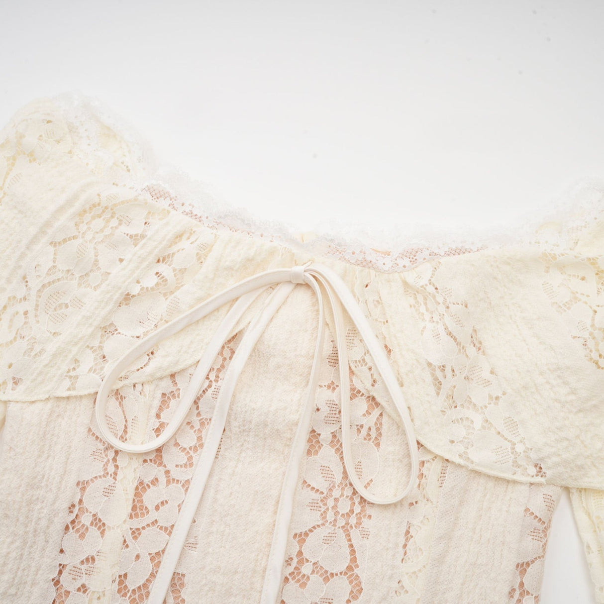 A neutral colored mini dress with floral lace pattern and flared cuffs named Émeline