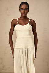 A neutralcolored long pleated maxi dress with side slits named Felicie