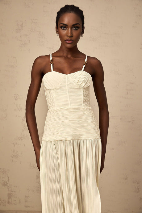 A neutralcolored long pleated maxi dress with side slits named Felicie