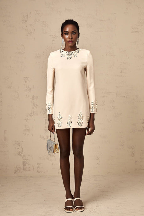 A neutralcolored longsleeved mini dress adorned with crystal embellishments featuring the Melissa design