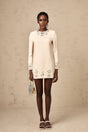 A neutralcolored longsleeved mini dress adorned with crystal embellishments featuring the Melissa design