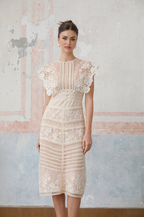 A neutralcolored midi dress with floral embroidery and lace detailing named Fleur