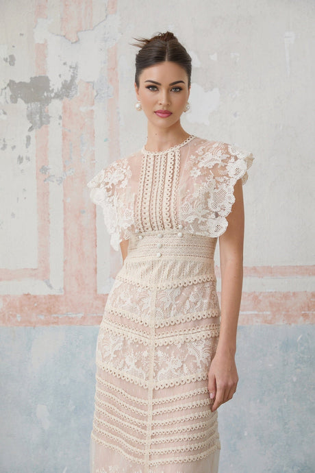A neutralcolored midi dress with floral embroidery and lace details featuring a delicate fleur pattern