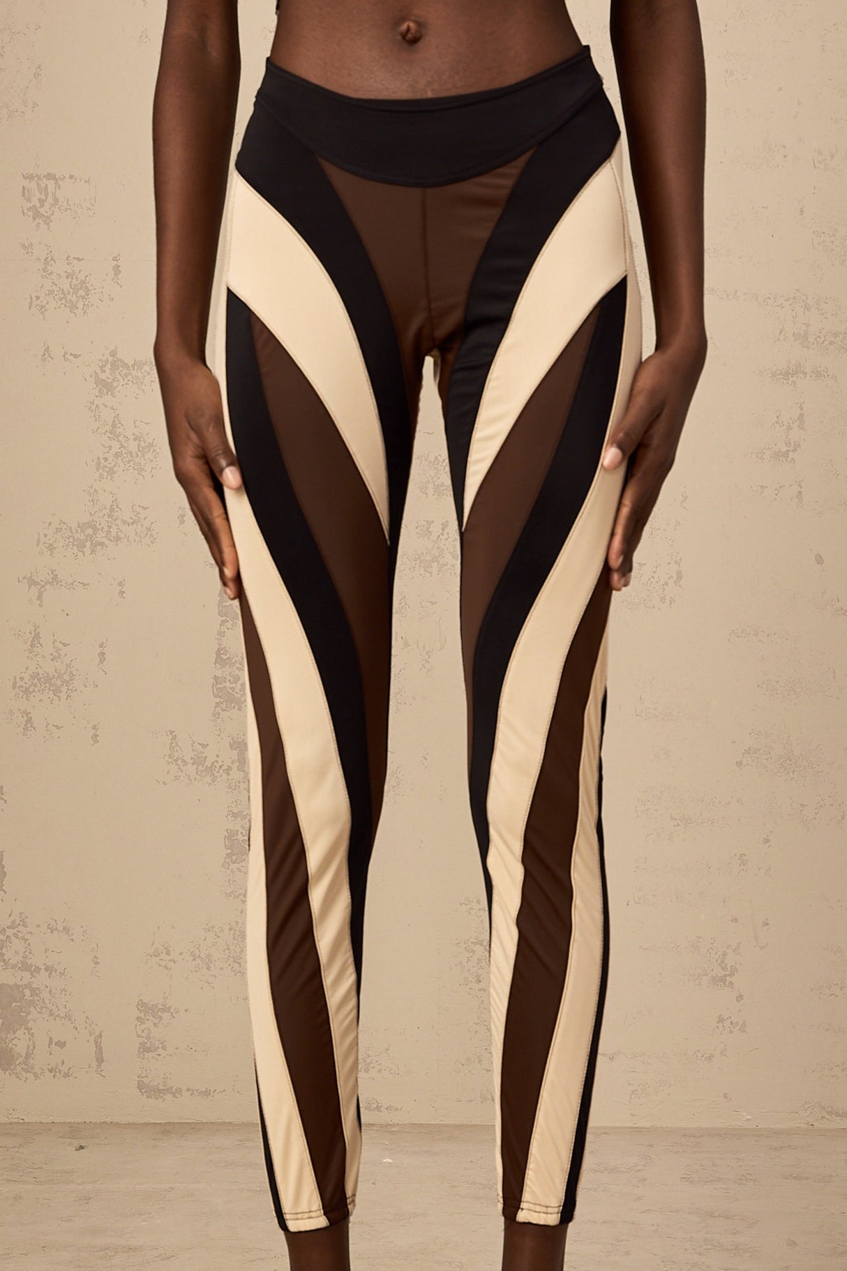 A pair of womens leggings featuring a spiral color block design with multiple panels in different colors