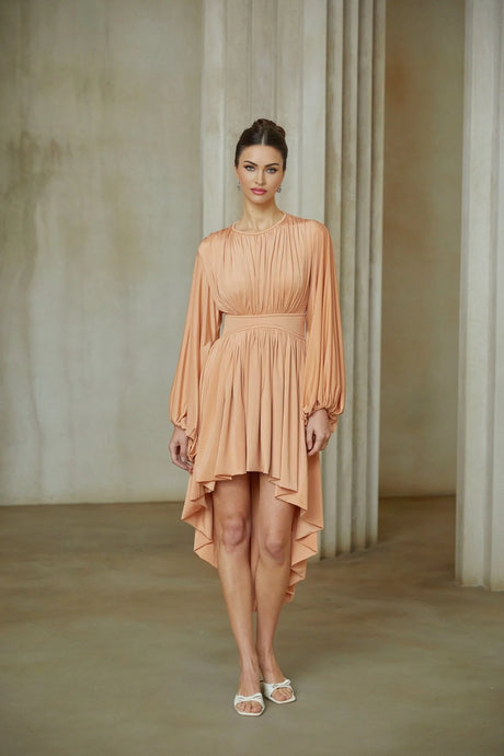 A pink asymmetrical midi dress with pleated details featuring a fitted bodice and flowy skirt