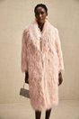 A pink faux fur coat with an open front design worn by a model against a plain background