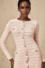 A pink fitted knit mini dress on a model showing its formfitting silhouette and short length