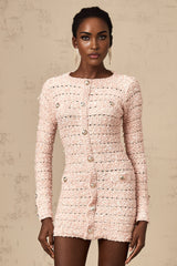 A pink fitted knit mini dress on a model showing the formfitting silhouette and short length