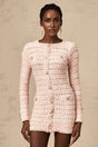 A pink fitted knit mini dress on a model showing the formfitting silhouette and short length