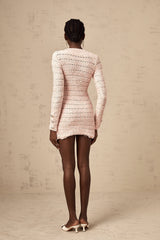 A pink fitted knit mini dress on a model showing the formfitting silhouette and short length