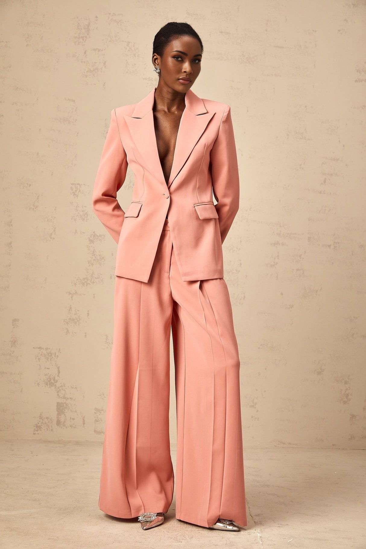 A pink matching set featuring a blazer and trousers with embroidery details and cutout design The blazer has an open front while the trousers are tailored Both pieces have decorative embroidery and strategic cutouts for a stylish look
