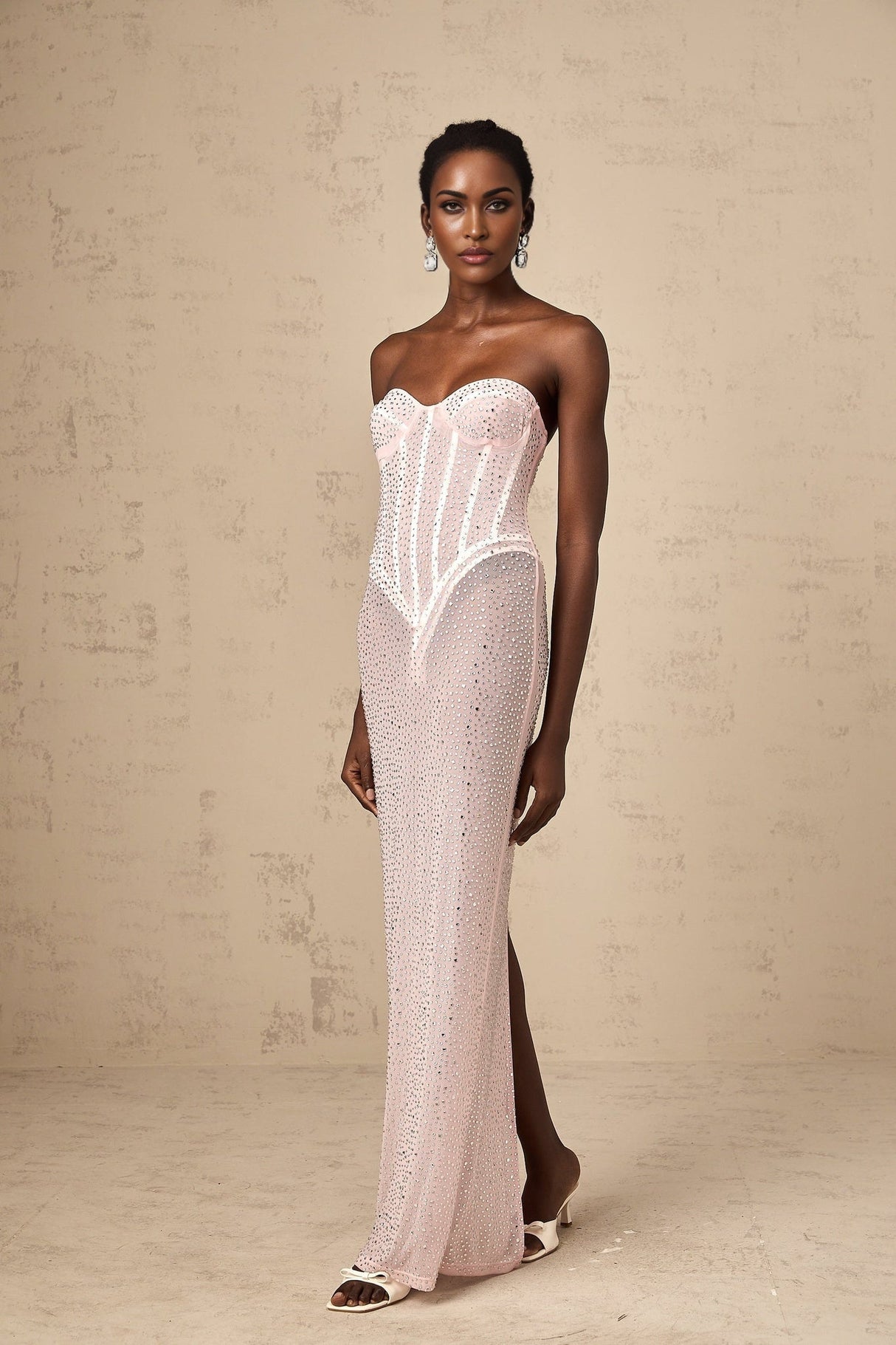A pink maxi dress with rhinestone embellishments and a semi sheer design featuring a long flowing silhouette