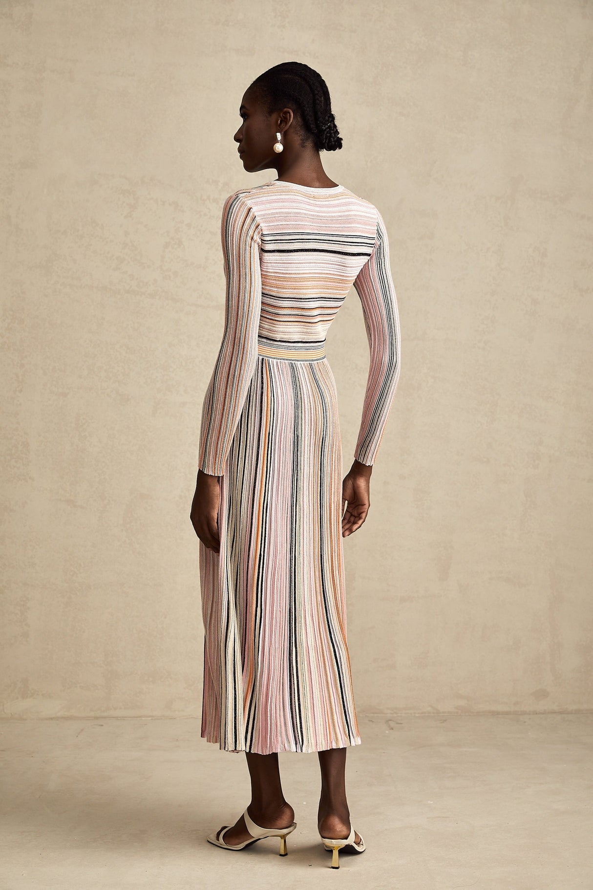 A pink metallic midi dress with pleated fabric named Mathilde featuring a shimmery finish and flowing design