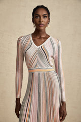 A pink metallic pleated midi dress with a shimmering finish named Mathilde featuring a flowing skirt that falls to mid calf length