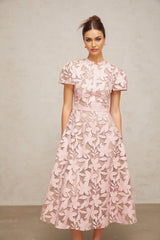 A pink midi dress made of guipure lace with intricate floral patterns and a delicate feminine design