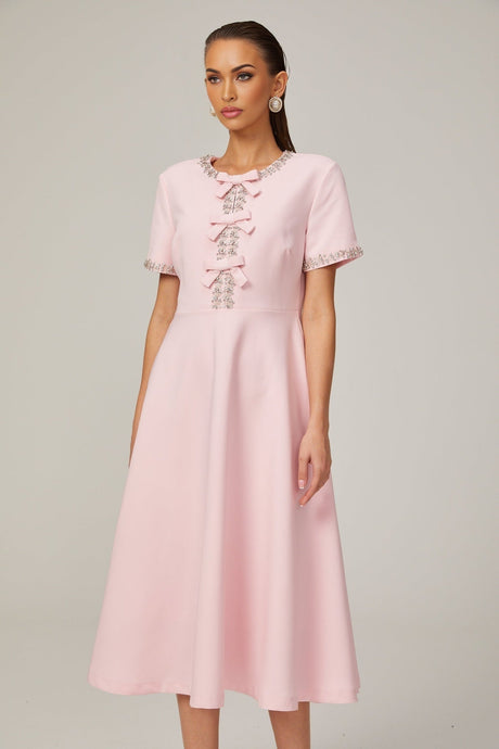 A pink midi dress with a crystalaccented bow detail and a fitted silhouette named Cassiopeia