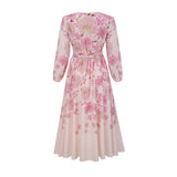 A pink midi dress with a floral print pattern worn by a model standing against a plain background